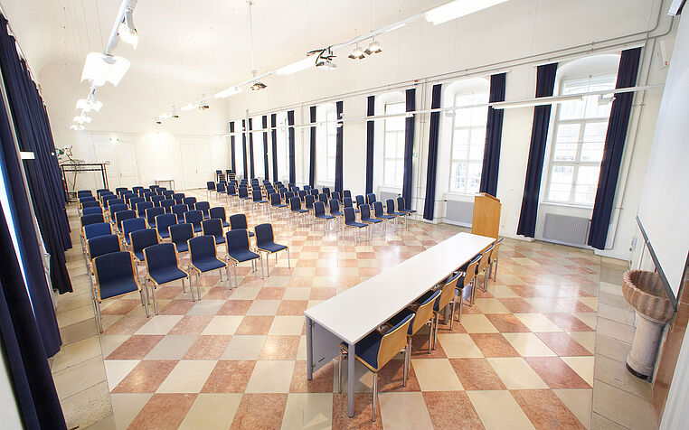 Bild: Foto der Aula am Campus mit Tisch und Sesselreihen